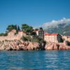Sveti Stefan, Montenegro, stunning island fortress with red-roofed buildings on the Adriatic Sea, framed by mountains.