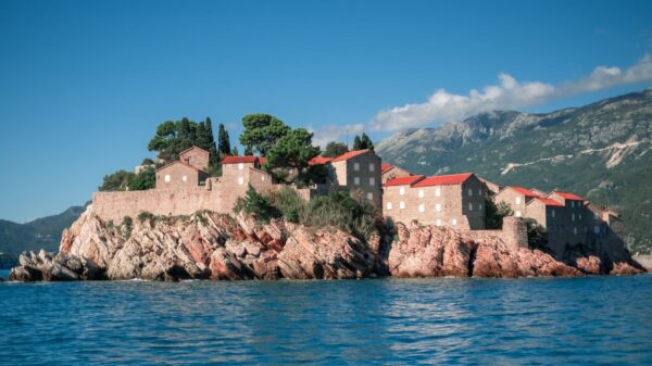 Sveti Stefan, Montenegro, stunning island fortress with red-roofed buildings on the Adriatic Sea, framed by mountains.