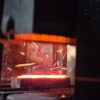 Close-up of glowing metal being forged, with bright sparks flying, capturing the industrial process.