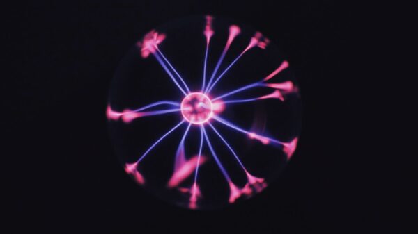 Transparent glass plasma ball with bright neon luminous against dark background in room