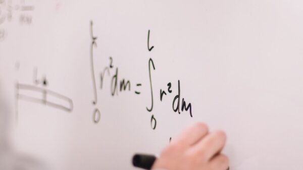 Person writing math equations on a whiteboard, focusing on integrals and formulas.