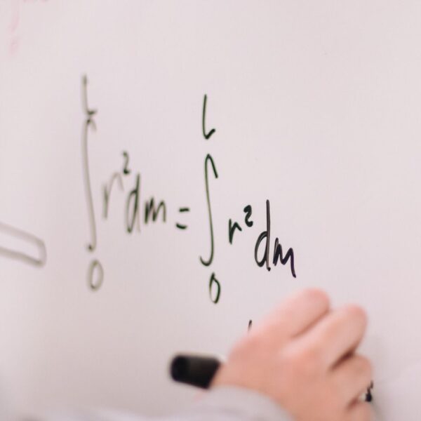 Person writing math equations on a whiteboard, focusing on integrals and formulas.