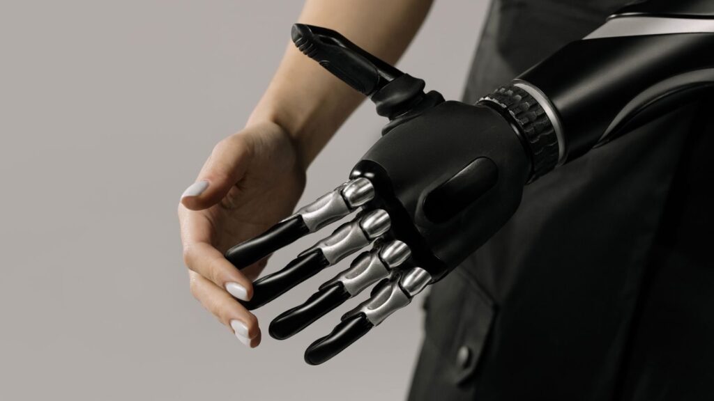 A futuristic black and chrome prosthetic arm being examined indoors, symbolizing technology integration.