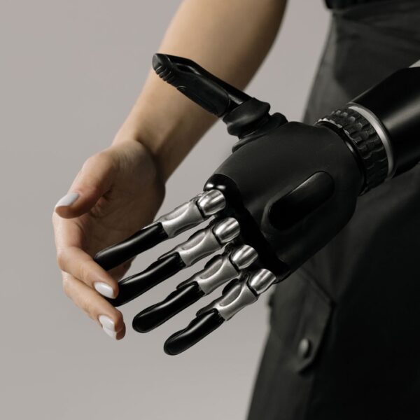 A futuristic black and chrome prosthetic arm being examined indoors, symbolizing technology integration.