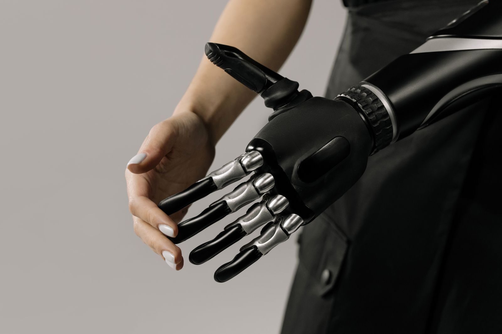 A futuristic black and chrome prosthetic arm being examined indoors, symbolizing technology integration.