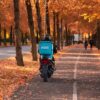 Motorbike delivery in autumnal Gothenburg with vibrant fall foliage.
