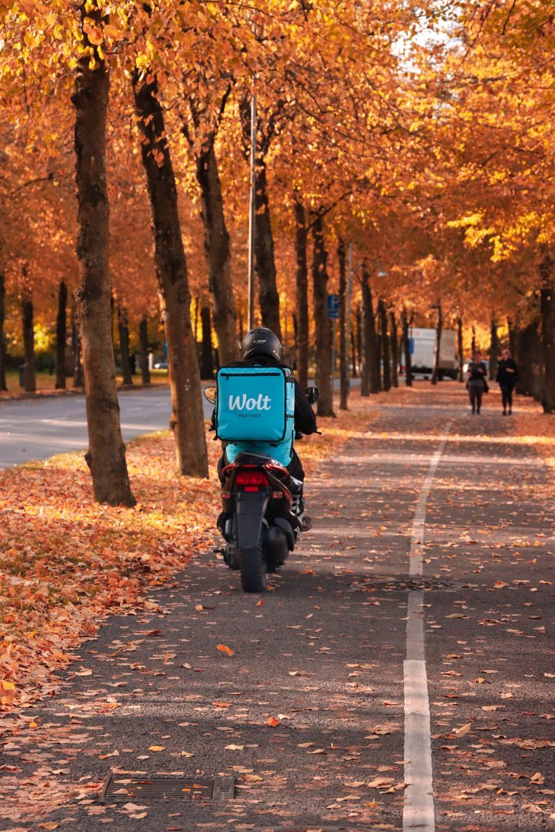 Motorbike delivery in autumnal Gothenburg with vibrant fall foliage.