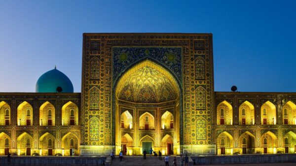 A stunning view of the Tilya-Kori Madrasah in Uzbekistan illuminated against a twilight sky, showcasing intricate architecture.