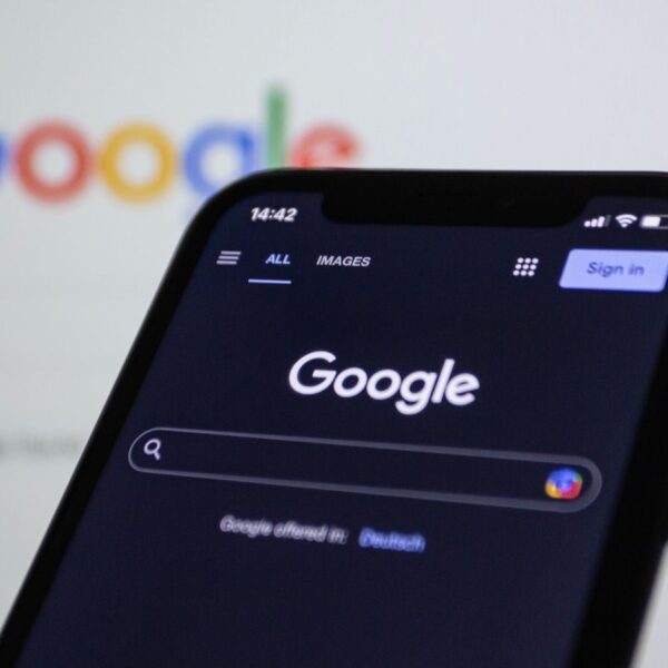 Smartphone screen showing Google search in dark mode with the Google logo in the background.
