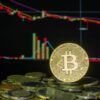 Bitcoin coin among stacked coins against a backdrop of a fluctuating financial market chart.