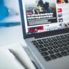 Open laptop displaying an online news article on a desk with a notebook nearby.