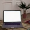 Open laptop with blank screen on a wooden table in a stylish interior setting.