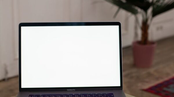 Open laptop with blank screen on a wooden table in a stylish interior setting.