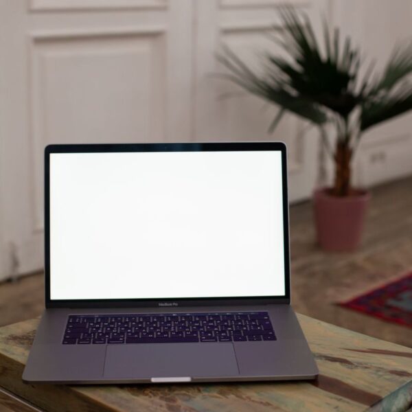 Open laptop with blank screen on a wooden table in a stylish interior setting.