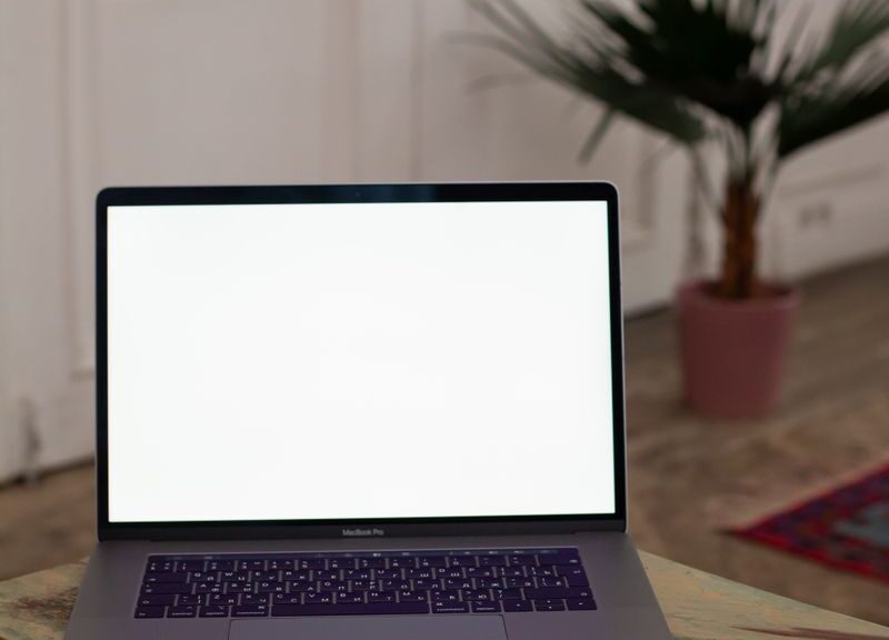 Open laptop with blank screen on a wooden table in a stylish interior setting.