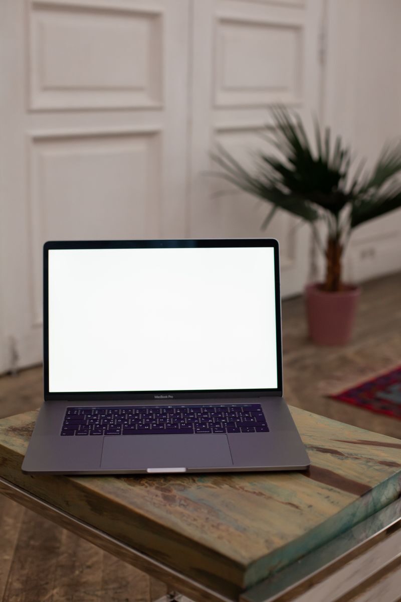 Open laptop with blank screen on a wooden table in a stylish interior setting.