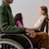 Group of diverse individuals posing in wheelchairs during a studio fashion shoot, showcasing stylish clothing.
