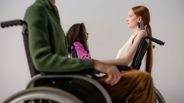 Group of diverse individuals posing in wheelchairs during a studio fashion shoot, showcasing stylish clothing.