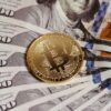 Gold Bitcoin coin resting on US dollar bills showcasing digital and traditional currency.