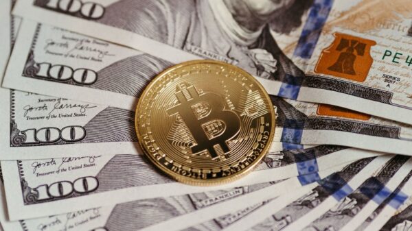 Gold Bitcoin coin resting on US dollar bills showcasing digital and traditional currency.