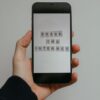 Close-up of a hand holding a smartphone displaying 'Break the Internet' on a gray background.