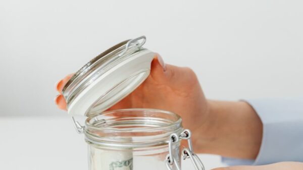 Close-up of hands placing money into a jar, symbolizing savings and financial planning.