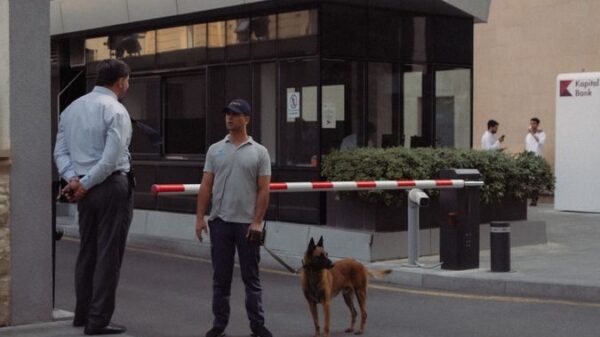 Security guard with a dog at a building entrance in Baku, Azerbaijan, emphasizing urban safety.