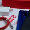 Flat lay of OnePlus 8 Pro unboxing with smartphone and accessories on white background.