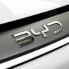 Detailed close-up of the chrome BYD logo on a car, showcasing sleek automotive branding.