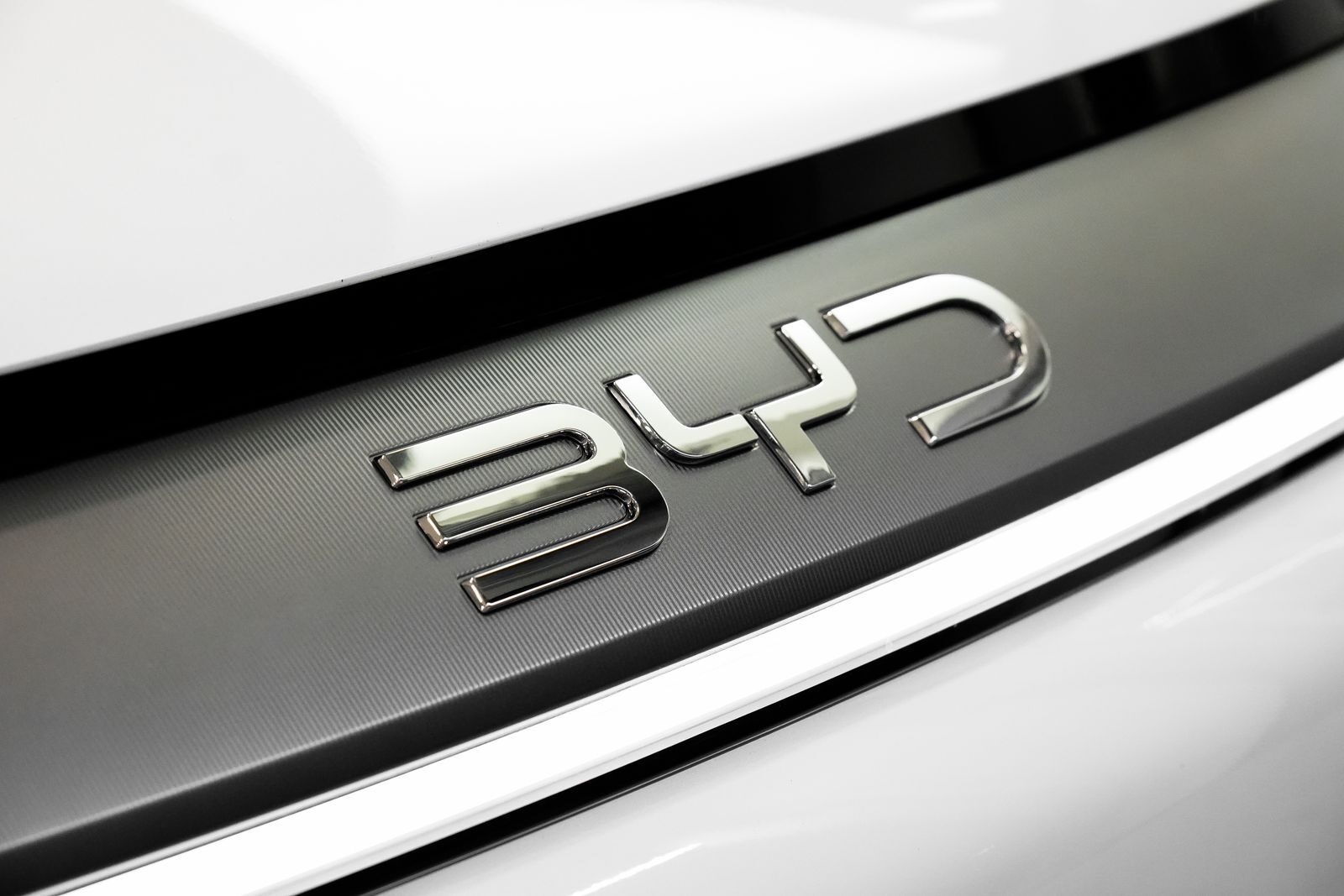 Detailed close-up of the chrome BYD logo on a car, showcasing sleek automotive branding.