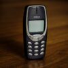 Small old mobile phone with monochrome screen and buttons placed on wooden table