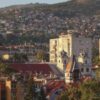 A picturesque view of Sarajevo cityscape with iconic buildings and surrounding hills at sunset.