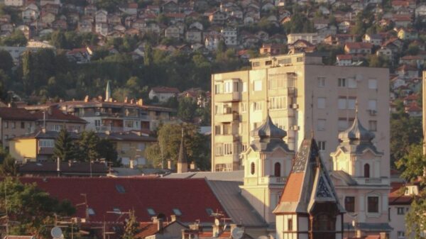 A picturesque view of Sarajevo cityscape with iconic buildings and surrounding hills at sunset.