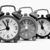 Monochrome image of three vintage alarm clocks highlighting the passage of time.